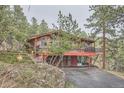 Elevated rustic home with wooden deck, garage, and stone retaining walls at 21191 Pleasant Park Rd, Conifer, CO 80433