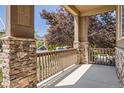 Covered front porch framed with stone columns and wooden railing providing a relaxing outdoor space at 25561 E 5Th Pl, Aurora, CO 80018