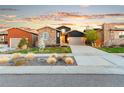 Charming home boasts stone and dark siding accents, complemented by a well-manicured front yard under a beautiful sunset sky at 17720 W 94Th Dr, Arvada, CO 80007