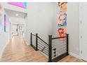 Bright hallway with wood floors, modern railing, and colorful wall art at 17720 W 94Th Dr, Arvada, CO 80007