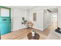 Sunlit living room features hardwood floors, a decorative plant and a green front door at 120 W Bayaud Ave, Denver, CO 80223