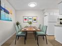 Bright dining room features modern light fixture, large window, dining table with six chairs, and vinyl flooring at 7645 E Quincy Ave # 105, Denver, CO 80237