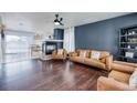Cozy living room featuring a dark accent wall, fireplace, and hardwood flooring at 15333 E 98Th Pl, Commerce City, CO 80022
