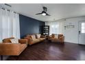 Comfortable living room with a modern ceiling fan, dark accent wall and wood floors at 15333 E 98Th Pl, Commerce City, CO 80022