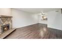 Bright living room with hardwood floors, stone fireplace, and view to kitchen at 3550 S Harlan St # 105, Denver, CO 80235