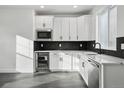 Stylish kitchen with white cabinets, black backsplash, stainless steel appliances, and modern fixtures at 16549 Black Rose Cir, Parker, CO 80134