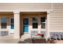 Exterior view of the home's front entrance featuring a vibrant blue door, covered porch, and manicured landscaping at 15800 E 121St Ave # 4G, Brighton, CO 80603