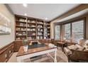 Well-lit home office with custom built-in shelving, a large desk, and comfortable seating at 14417 W 57Th Pl, Arvada, CO 80002