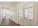 Bright hallway featuring hardwood floors and charming french doors leading to another room at 1842 Chaffee Crest Dr, Berthoud, CO 80513