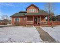 Charming home featuring a cozy front porch and beautifully landscaped front yard covered with snow at 225 Longspur Dr, Brighton, CO 80601