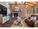 Cozy living room with stone fireplace, wood ceiling beams, and expansive windows offering natural light at 31607 Broadmoor Dr, Evergreen, CO 80439
