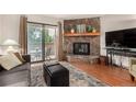 Living room featuring a stone fireplace, balcony, hardwood floors and neutral color palette at 7750 W 87Th Dr # C, Arvada, CO 80005