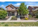 Inviting home with covered porch and stone details, complemented by green landscaping and a sunny sky at 10859 E 25Th Dr, Aurora, CO 80010