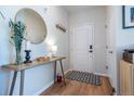 Inviting entryway featuring a round mirror, wooden table, decorative accents, coat hooks, and stylish flooring at 4630 Copeland Cir # 201, Highlands Ranch, CO 80126