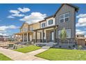 New construction home featuring a covered porch, stone accents, and professionally landscaped yard at 21022 E 63 Dr, Aurora, CO 80019