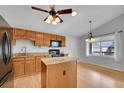 The kitchen has granite countertops, an island, wood cabinets, and modern black appliances at 4825 S Ammons St # 133, Littleton, CO 80123