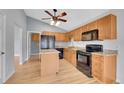 Well-equipped kitchen featuring an island, sleek black appliances, granite countertops, and wood cabinets at 4825 S Ammons St # 133, Littleton, CO 80123