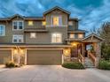 Attractive townhome with stone accents, two-car garage, and inviting front entrance with warm lighting at 7648 S Sicily Way, Aurora, CO 80016