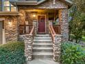 Inviting front porch with stone columns, wooden railing, and a charming wreath on the front door at 7648 S Sicily Way, Aurora, CO 80016