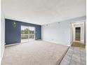 Spacious living room with neutral carpet, blue accent wall, and sliding glass doors to the balcony at 190 E Highline Cir # 302, Centennial, CO 80122
