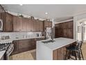 Spacious kitchen featuring stylish dark wood cabinetry, a large island, and stainless steel appliances at 8850 W Cannes Dr, Littleton, CO 80127