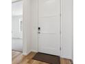 Modern hallway with wood floors leading to a bright, carpeted room and a white door at 230 Lark Sparrow Way, Bennett, CO 80102