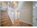 Bright foyer features hardwood floors, staircase with white railing, and multiple entrances at 2882 Signal Creek Dr, Thornton, CO 80241
