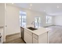 Modern kitchen with white cabinets, island with sink, and stainless steel appliances at 5553 Wisteria Ave, Firestone, CO 80504