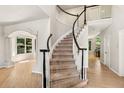Elegant foyer showcasing a curved staircase with black and white banisters and hardwood floors at 6429 S Jamaica Cir, Englewood, CO 80111