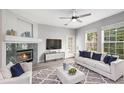 Bright living room with a modern ceiling fan, a corner fireplace, and a white sofa with blue accent pillows at 3952 S Carson St # 103, Aurora, CO 80014