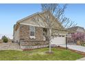 Landscaped front yard of house with stone accents, a tree, and a well-maintained lawn at 15211 Quince St, Thornton, CO 80602