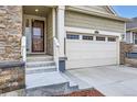 Home's front entryway with a two-car garage, featuring stone details and an inviting entrance at 15211 Quince St, Thornton, CO 80602