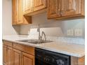 This updated kitchen features wood cabinetry, a black dishwasher, stainless steel sink, and a light countertop at 10792 E Exposition Ave # 154, Aurora, CO 80012