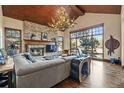 Inviting living room with stone fireplace, wood-beam ceiling, antler chandelier, and a large window view at 77 Comstock Pl, Castle Rock, CO 80108