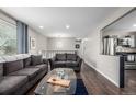 Open living room with hardwood floors, two sofas, and an adjacent, updated kitchen at 3134 S Fairplay St, Aurora, CO 80014