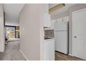 Galley kitchen showcases modern, white appliances, cabinets and view into an open living room with fireplace at 8879 W Floyd Ave, Lakewood, CO 80227