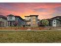 Stylish two-story home at sunset, showcasing a stone facade, balcony, and beautifully landscaped front yard at 6054 N Perth St, Aurora, CO 80019