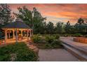 Relaxing gazebo with hanging flowers, alongside a stone fire pit and lush landscaping at 7472 S Utica St, Littleton, CO 80128