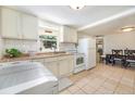 Bright kitchen featuring white cabinetry, tile flooring, and adjacent dining area for easy meals at 11940 W Independence Ave, Lakewood, CO 80401