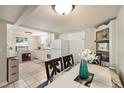Bright kitchen featuring white cabinetry, tile flooring, and adjacent dining area for easy meals at 11940 W Independence Ave, Lakewood, CO 80401