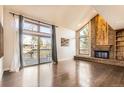 Bright living room with a brick fireplace, large windows, and sliding door access to the deck with hardwood floors at 8159 Lodgepole Trl, Lone Tree, CO 80124