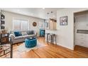 Bright living room featuring hardwood floors, a comfortable sofa, and a stylish blue tufted ottoman at 1575 Verbena St, Denver, CO 80220