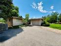 Single-story home featuring an attached garage, mature trees, and a long driveway at 6040 W Elmhurst Dr, Littleton, CO 80128