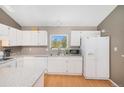 Bright kitchen with white cabinets, stainless appliances, and lovely view from the window at 30819 Hilltop Dr, Evergreen, CO 80439