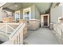 Inviting covered porch featuring stone pillars, wooden railings, and stylish front door entrance at 872 S Flat Rock Way, Aurora, CO 80018