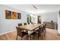 Bright dining room with a modern table set, wood floors, and three unique pieces of modern art at 9673 Pinebrook St, Highlands Ranch, CO 80130
