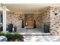 Cozy front porch with brick details, a wood front door, and decorative planters at 9837 E Aberdeen Ave, Englewood, CO 80111