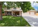 Inviting two-story home featuring a brick facade, three-car garage and mature trees at 9837 E Aberdeen Ave, Englewood, CO 80111