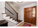 Welcoming home foyer featuring a staircase with wood and iron railing and a unique front door at 9837 E Aberdeen Ave, Englewood, CO 80111