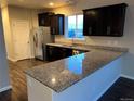 Modern kitchen featuring granite countertops, dark wood cabinets, and stainless steel appliances at 3231 Lump Gulch Way, Erie, CO 80516